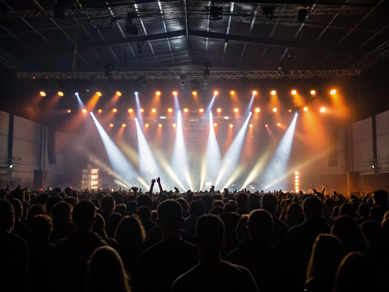 Silhouette of cheering crowd against stage lights